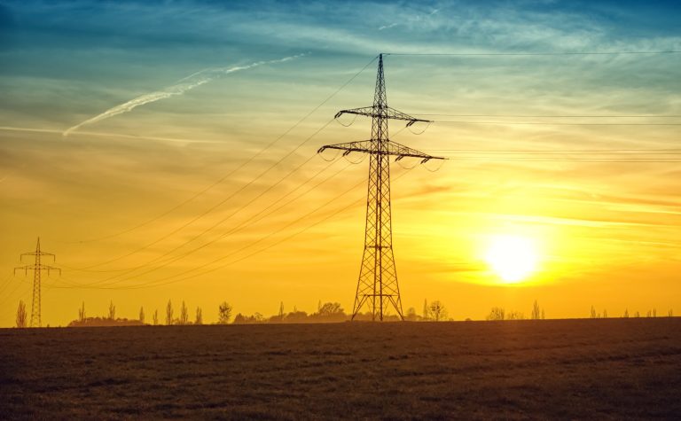 brown transmission towers on field during sunset landscape photography